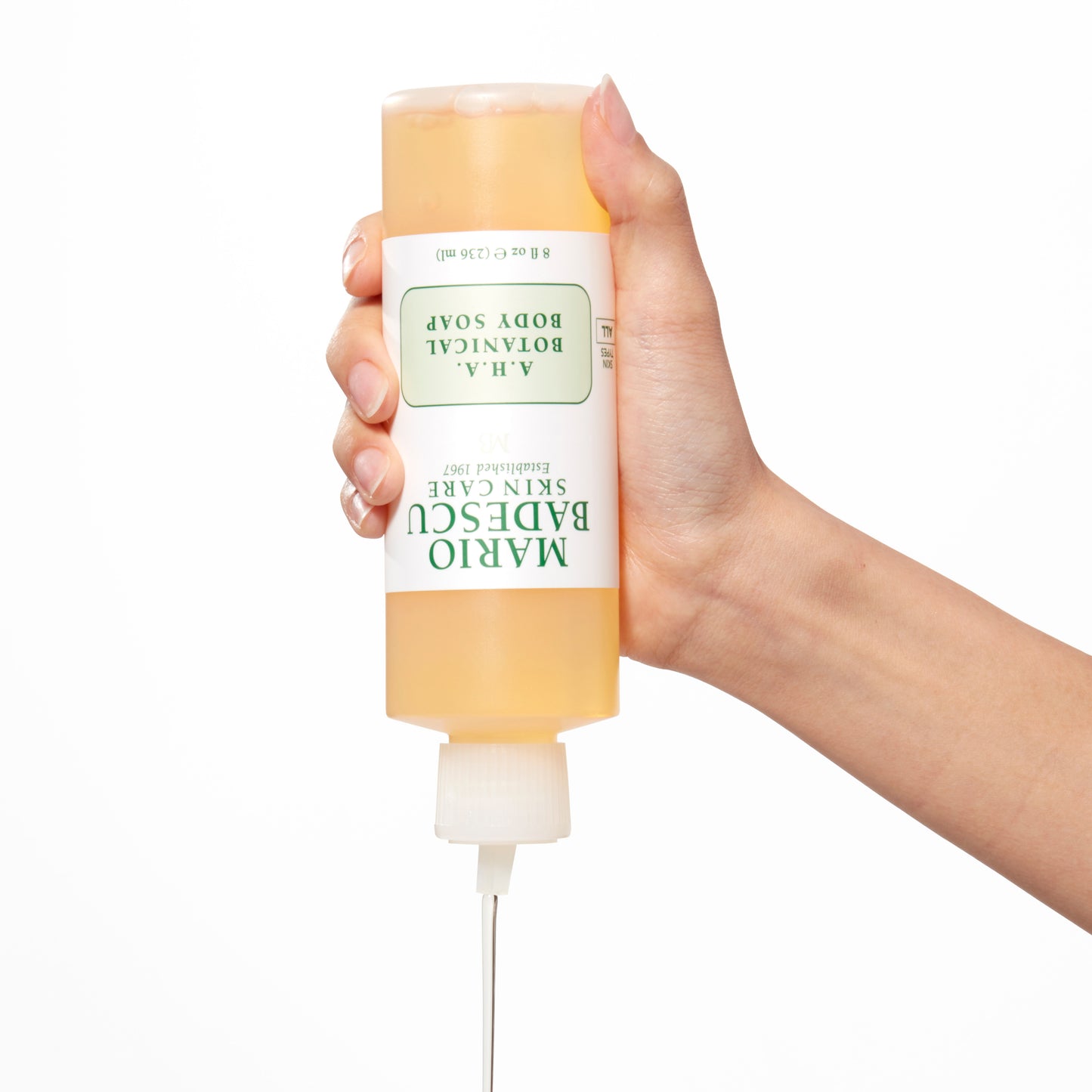Demonstration showing a woman's hand squeezing A.H.A. Botanical Body Soap bottle