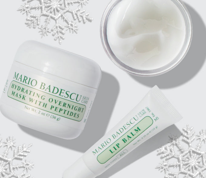 Mario Badescu skincare products including a jar, lip balm, and cream on a light background with snowflake decorations.