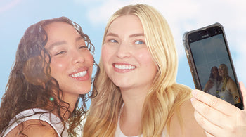 Two women taking a selfie with a phone against a blue sky background