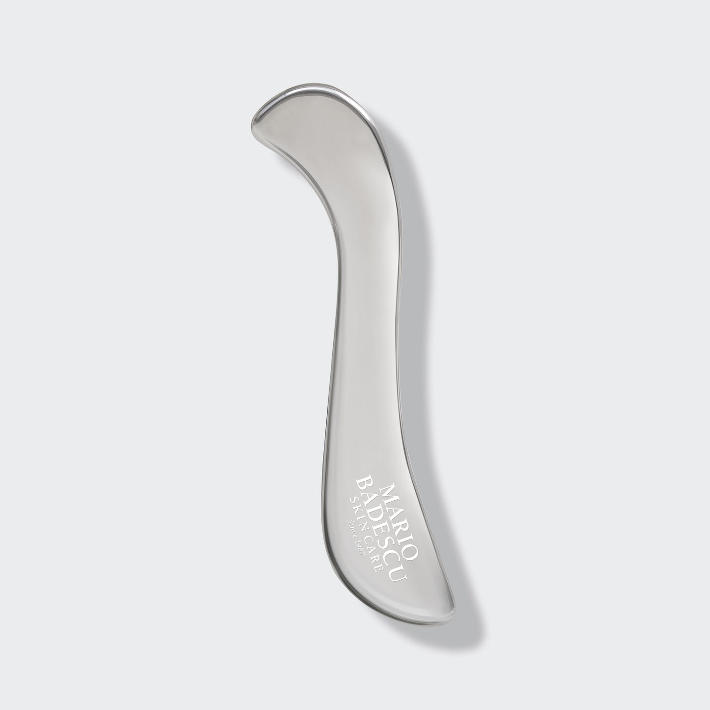 Silver facial roller with 'Mario Badescu' branding on a light gray background