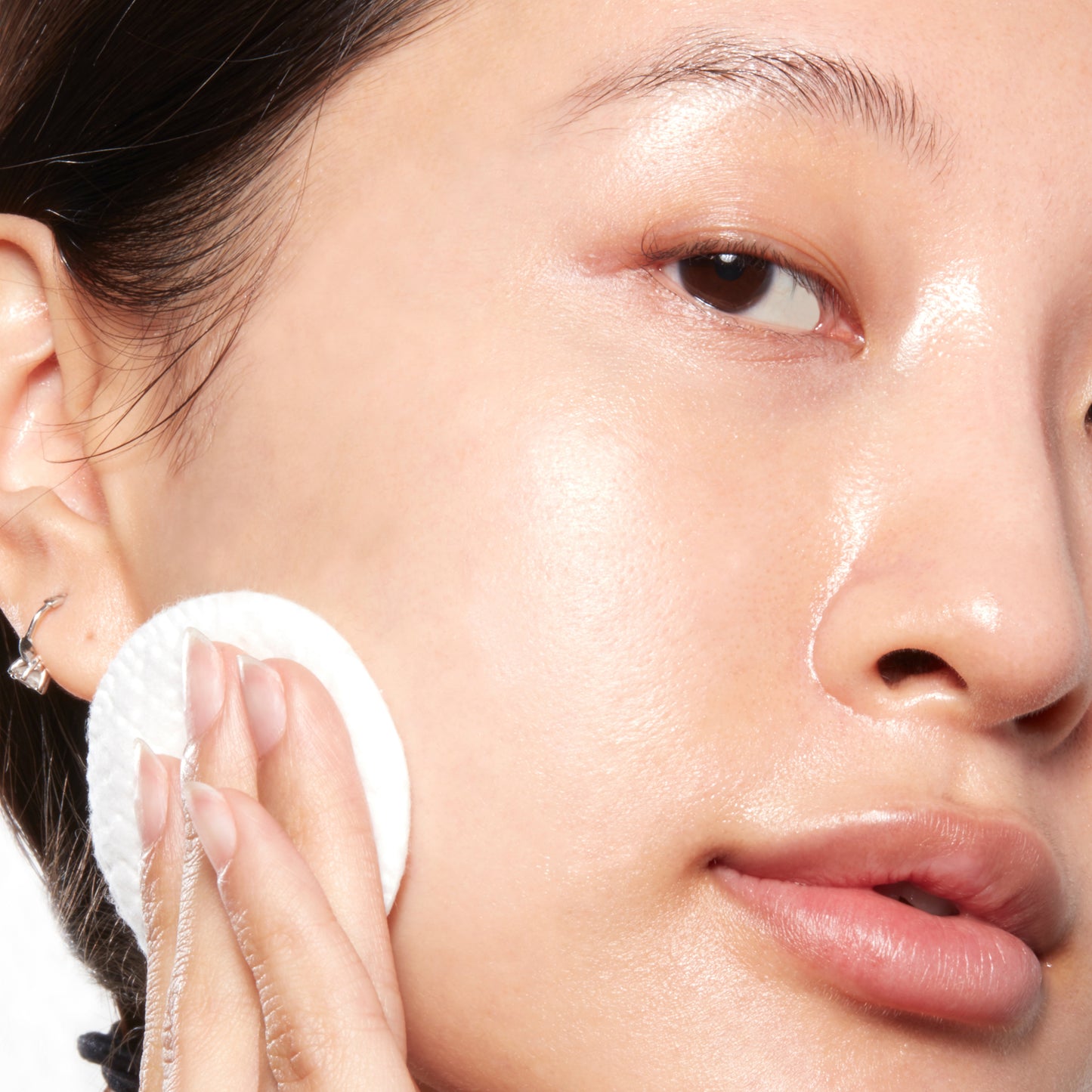 Woman with glowing skin applying Glycolic Acid Toner with a cotton pad