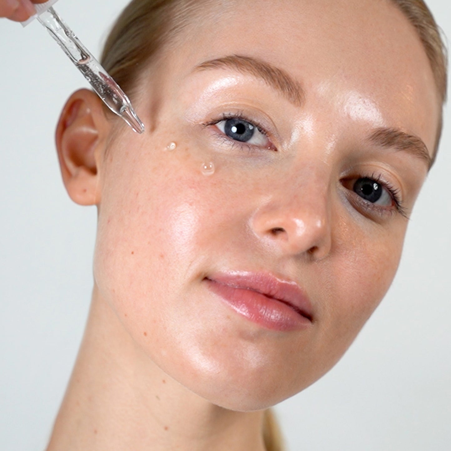 Woman demonstrating how to apply Azelaic Acid Serum